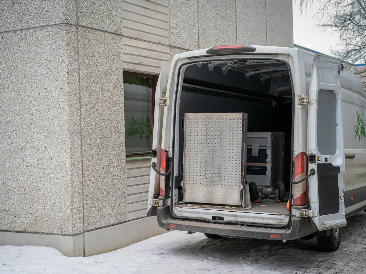 White delivery van parked by a building with its back doors open