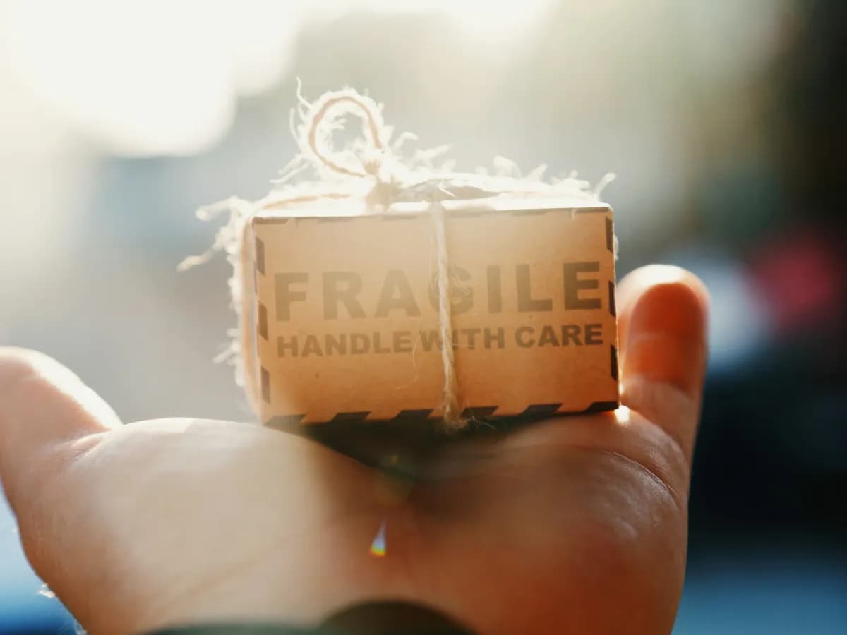 A small box marked "Fragile, handle with care" resting on a hand