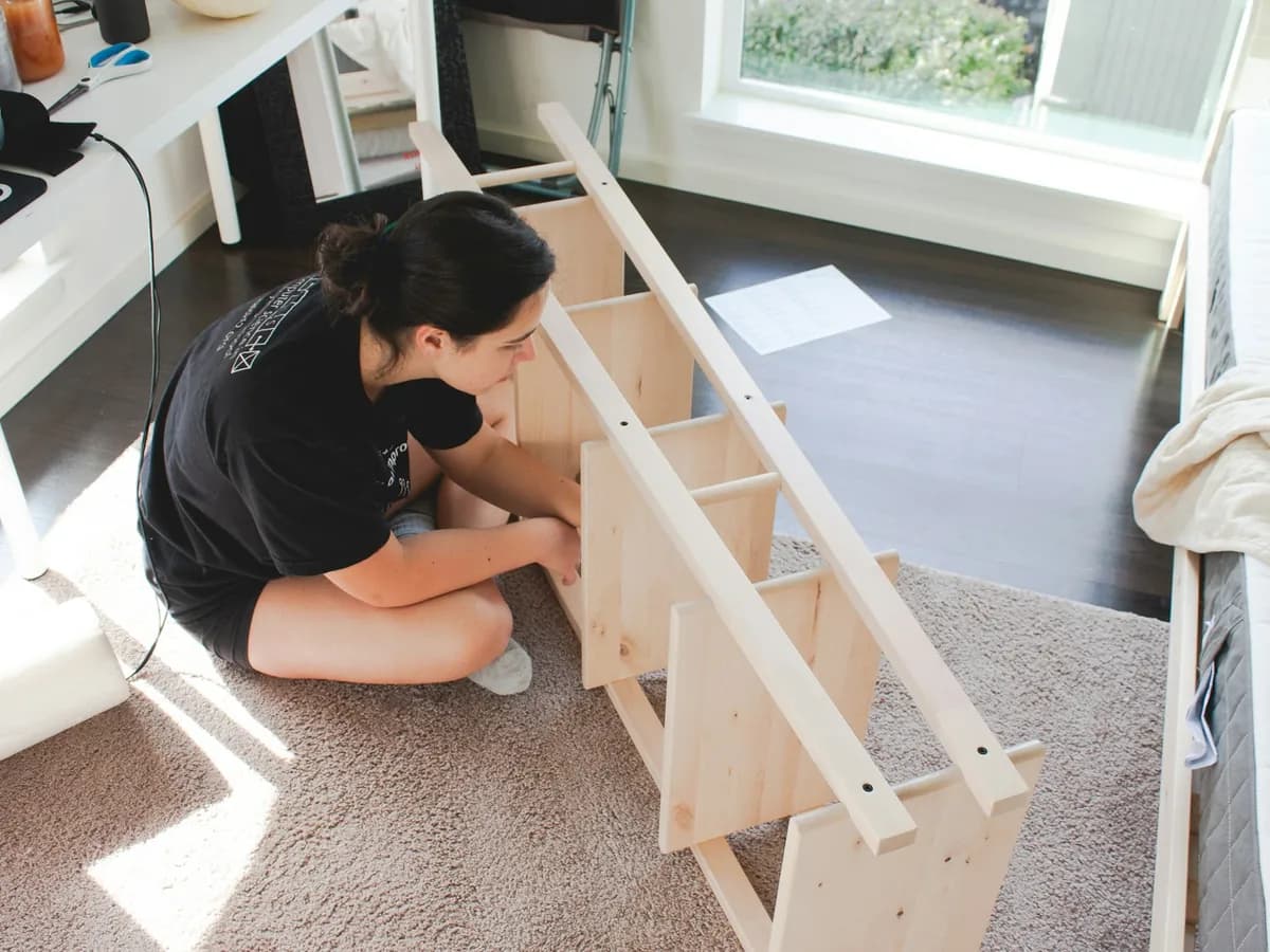 A person assembling a wooden shelf unit on the floor