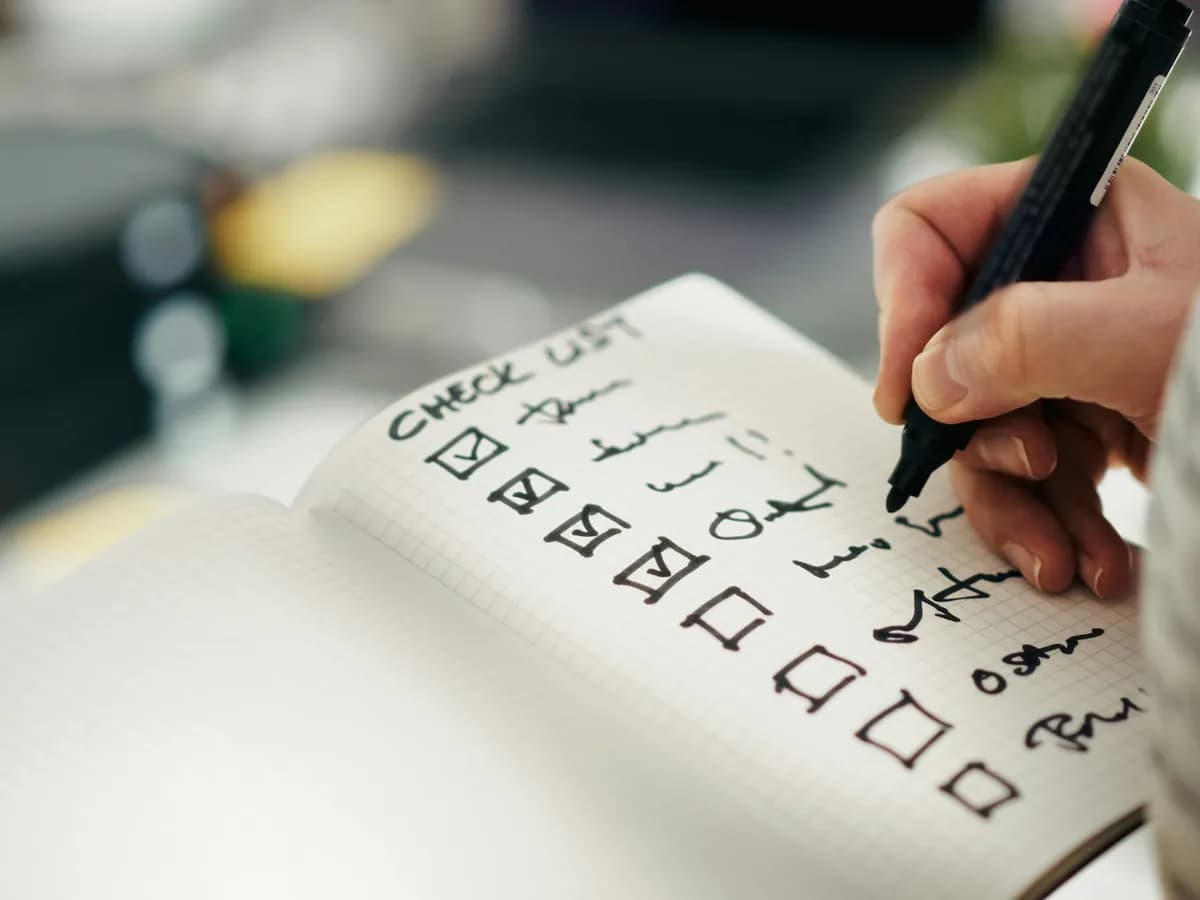 A hand writing a moving checklist in a notebook